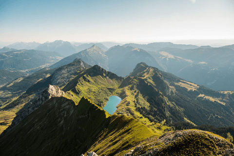 An aerial view of green mountain ridges under a hazy sky.